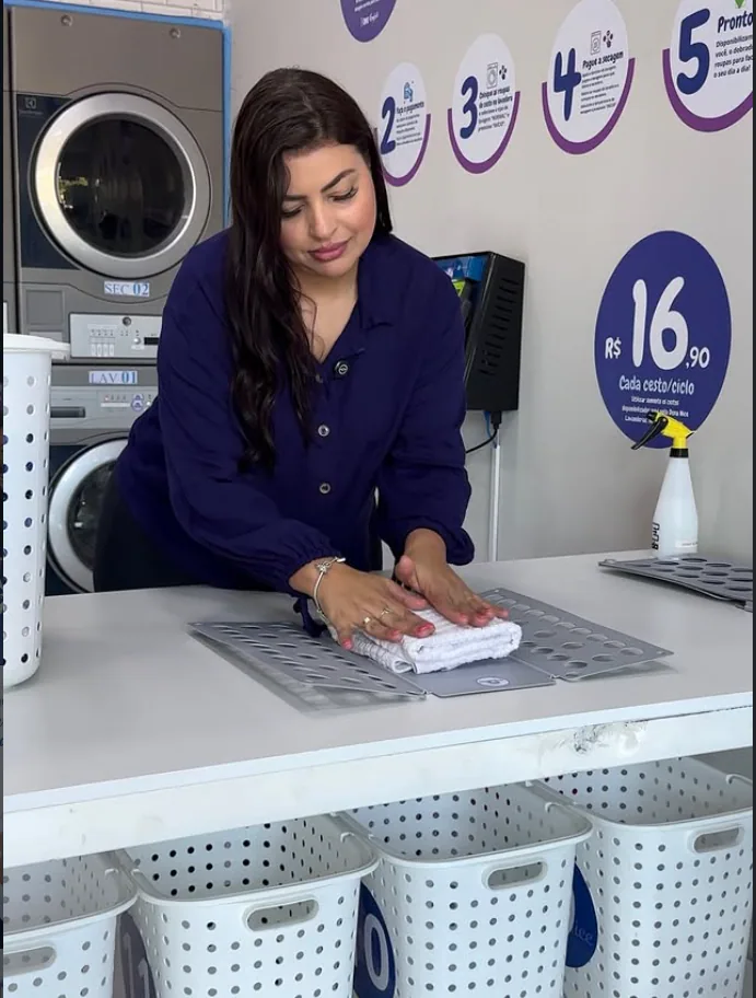 Cliente dobrando roupas limpas na Dona Nice Lavanderia